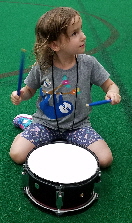 Girl Playing Drum at Petting Zoo at Concert